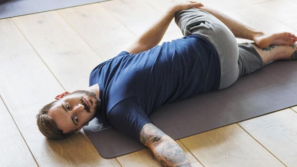 Un homme est allongé sur un tapis de yoga et fait un exercice.
